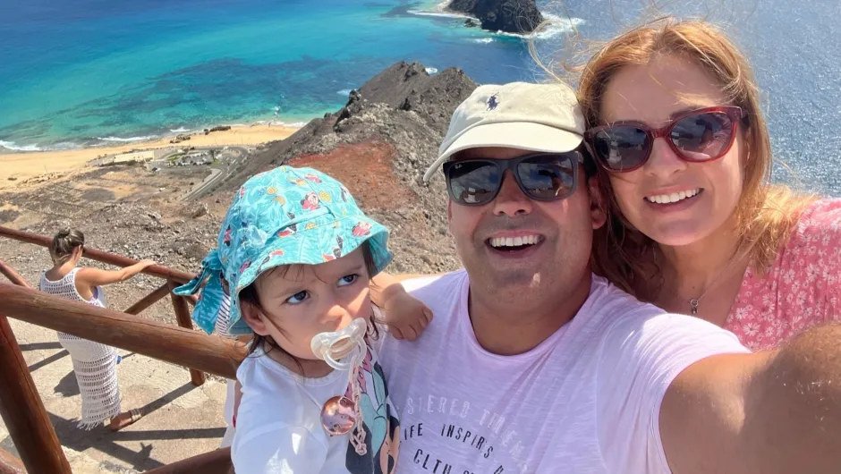 Ein Mann und eine Frau, die ein Baby halten, das alle anlächeln.