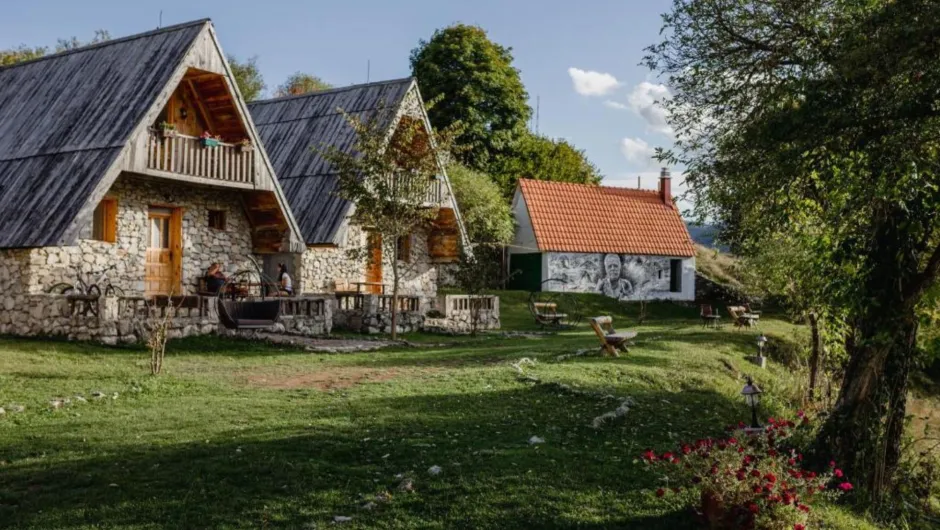 Traditionelles Hüttendorf mit Steinhäusern und blühendem Garten.