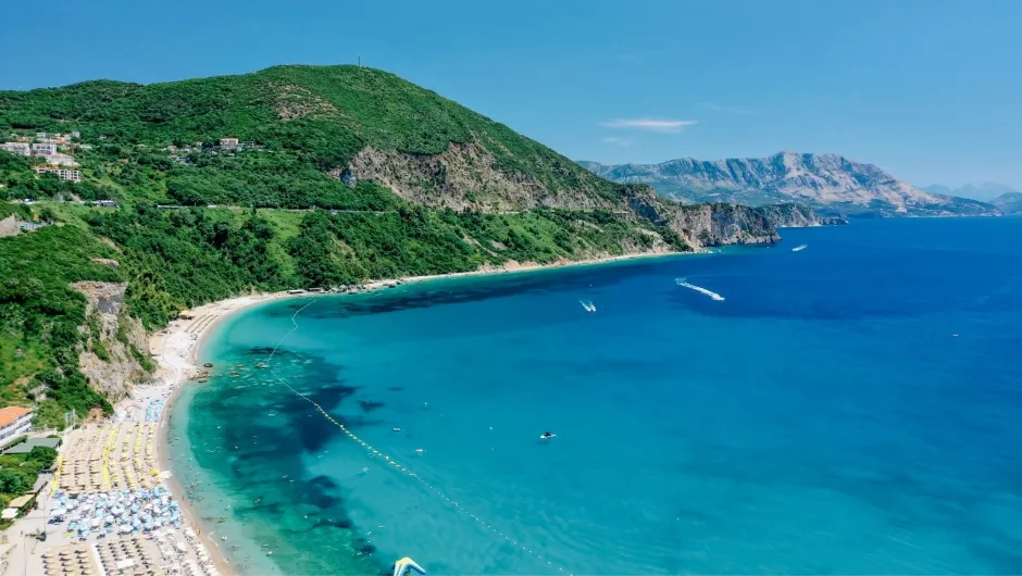 Türkisblaue Bucht in Montenegro, umgeben von grünen Hügeln und Felsküste.