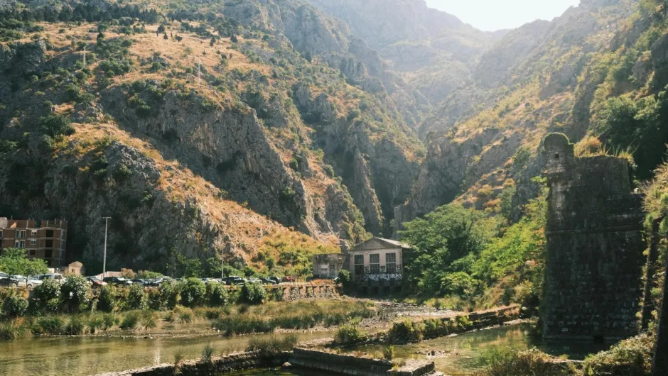 Schroffe Berglandschaft bei Kotor in Montenegro mit Fluss, altem Gemäuer und grün bewachsenen Hängen.