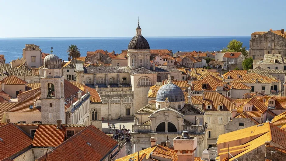 Blick auf Dubrovniks Altstadt mit roten Dächern, historischen Gebäuden und dem Meer im Hintergrund.