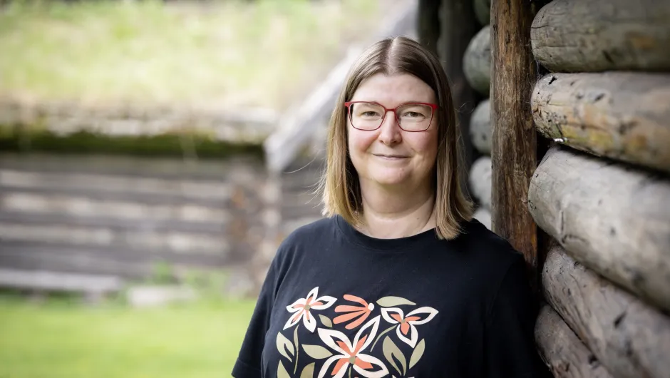 Schweden Reisexpertin Sylvia vor einem typisch schwedischen Holzhaus inmitten der Natur.