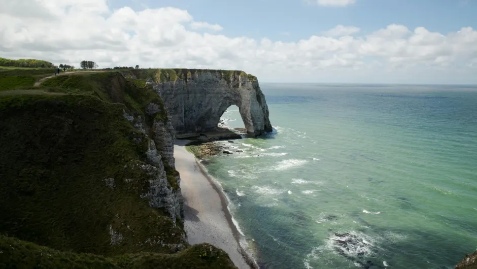 Kreidefelsen mit natürlichem Felsbogen bei Étretat in der Normandie, mit Blick auf das Meer und einen schmalen Strand.