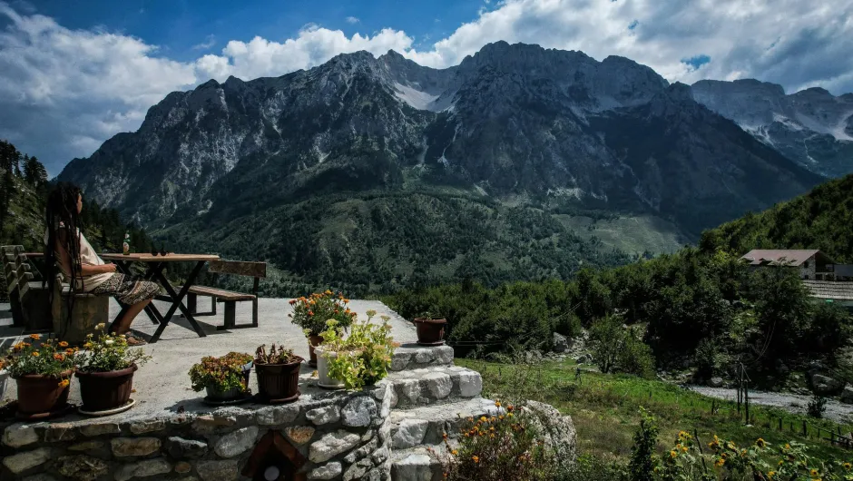 Frau sitzt auf einer Terrasse im Valbona-Tal in Albanien mit Blick auf die albanischen Alpen.