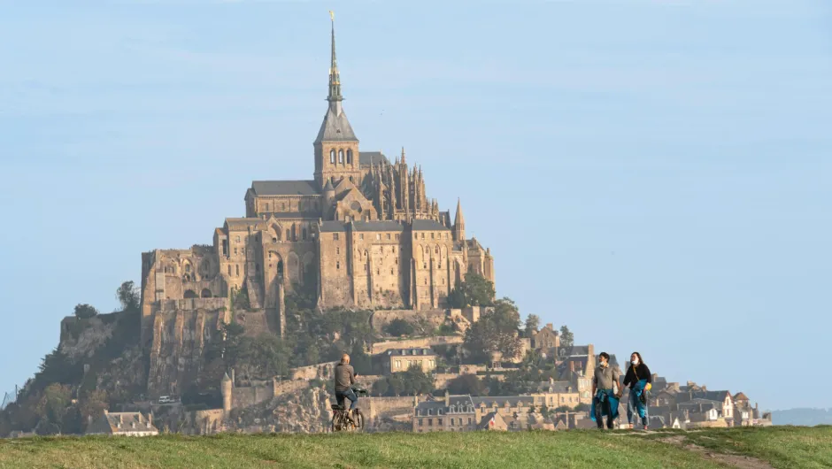 Blick auf den Mont-Saint-Michel in Frankreich mit Radfahrer und Spaziergängern im Vordergrund.