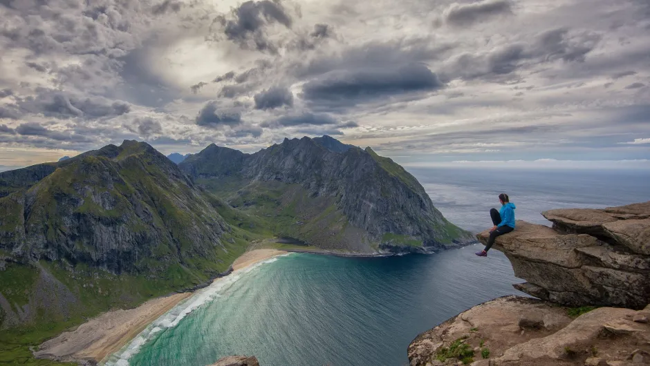 Frau auf einem Berggipfel in Norwegen, mit Ausblick uaf einen Fjord.