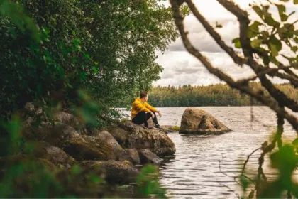 Ein Mann sitzt auf einem Stein während seiner Finnland Reise