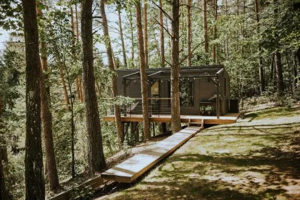 Eine Holzhütte im Wald mit Sonnenschein, Lettland.
