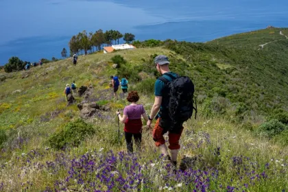 Hiking mit Blick auf blühende Frühlingswiese und Meer.