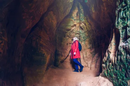 Eine Touristin mit roter Jacke entdeckt eine Höhle in Sigulda, Lettland.