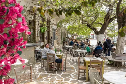 gemütliches Außencafé mit mehreren Tischen und Stühlen auf einer steinernen Terrasse.