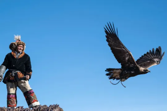 Ein Mann steht auf einem Stein und ein Adler fliegt von ihm weg