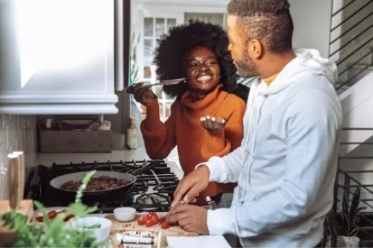 Zwei Personen stehen am Herd und kochen zusammen