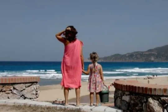 Eine Mutter steht mit ihrem Kind am Strand in Sardinien