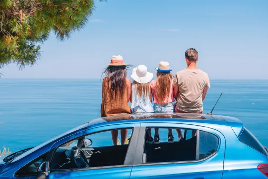 Familie auf Auto bei einer Mietwagenrundreise.