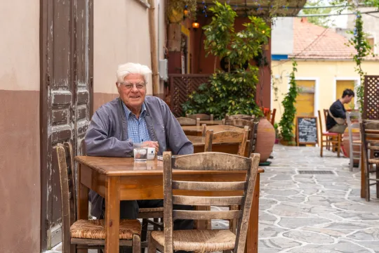 Ein Person sitzt in einem Cafe draussen.