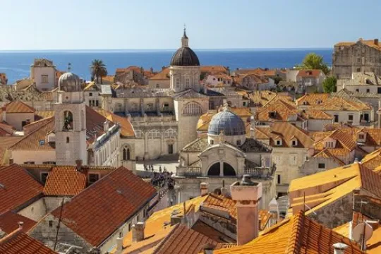 Blick auf Dubrovniks Altstadt mit roten Dächern, historischen Gebäuden und dem Meer im Hintergrund.