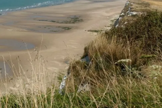 grasbewachsenen Klippe und das blaue Meer mit Schiffen am Horizont.