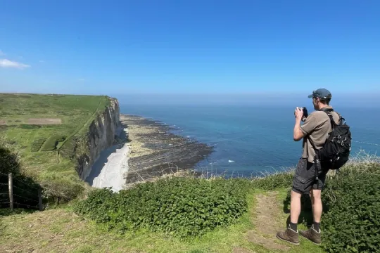 Wanderer auf dem GR223 an der normannischen Küste mit Blick auf steile Klippen und das Meer.